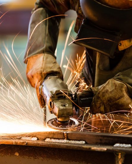 Electric wheel grinding on steel structure in factory